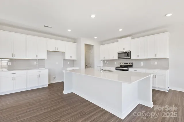 a kitchen with stainless steel appliances a refrigerator sink and white cabinets