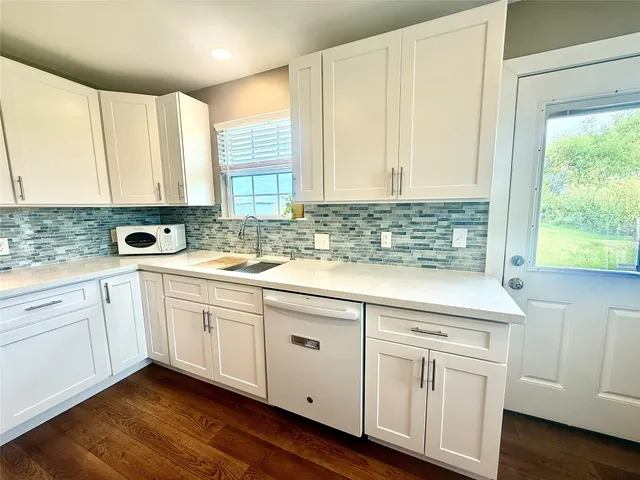 a kitchen with white cabinets window and sink
