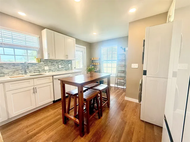 a kitchen with stainless steel appliances a table chairs refrigerator and sink