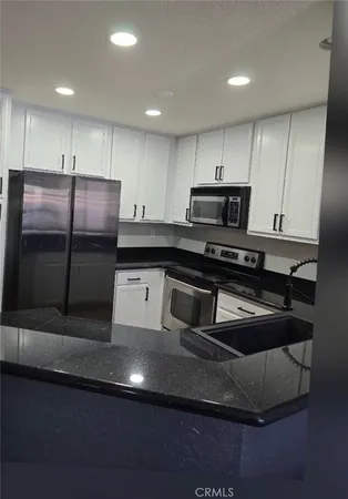 a kitchen with kitchen island stainless steel appliances a sink a stove a refrigerator a microwave and cabinets