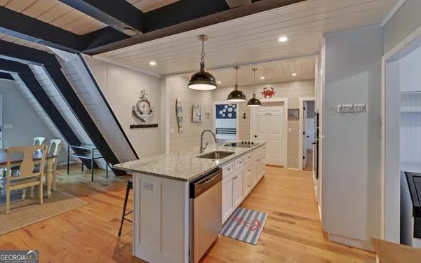 a kitchen with stainless steel appliances granite countertop a refrigerator a oven a sink and a dining table with wooden floor