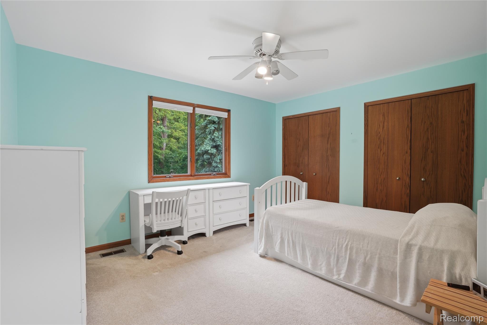 68345 Romeo Plank Road Ray, MI 48096 - Photo 37 of 52 Spacious room featuring light blue walls, light-colored carpeting, a ceiling fan with integrated lighting, a large window with natural wood trim, and two built-in closets with wood doors