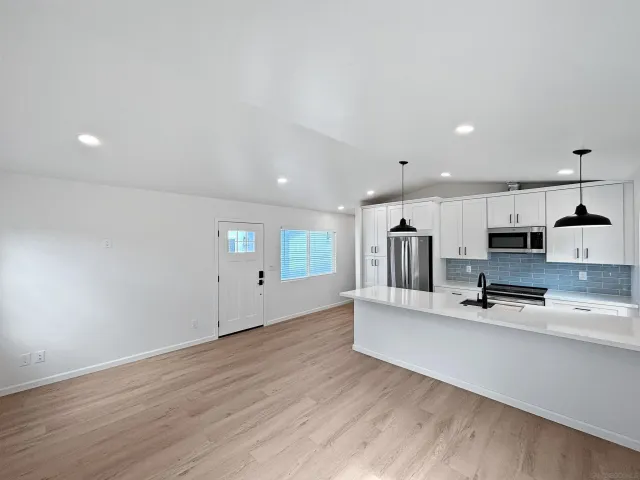 a large white kitchen with a sink and dishwasher a stove with wooden floor