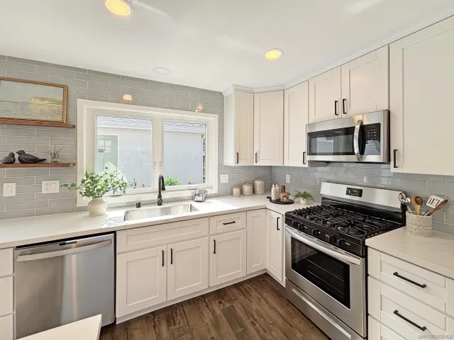 a kitchen with white cabinets and appliances
