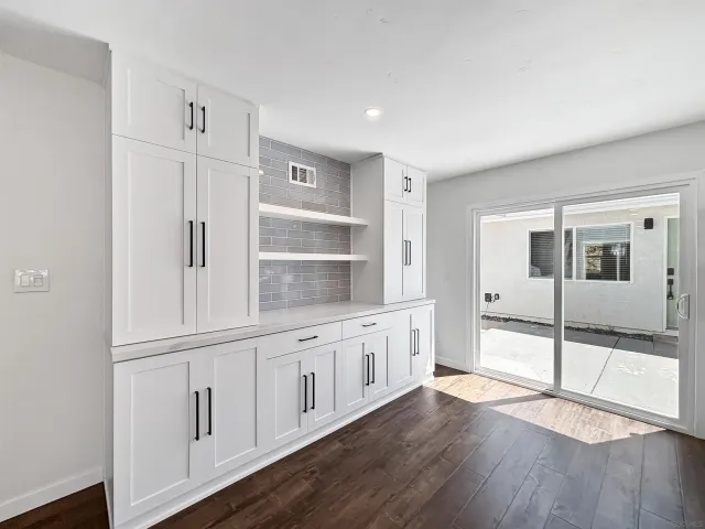 a kitchen with white cabinets and wooden floor