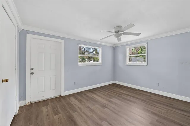 a view of empty room with wooden floor and ceiling fan