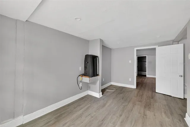 a view of an empty room with wooden floor and bathroom