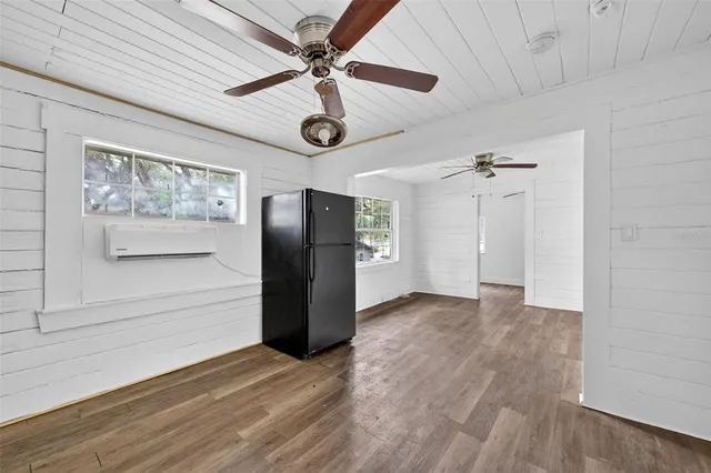a view of an empty room with wooden floor and a ceiling fan
