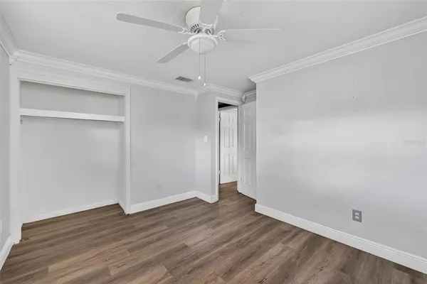 an empty room with wooden floor and ceiling fan