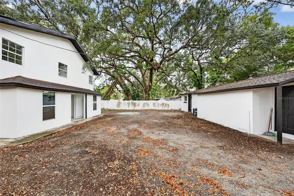 a backyard of a house with large trees and a tree