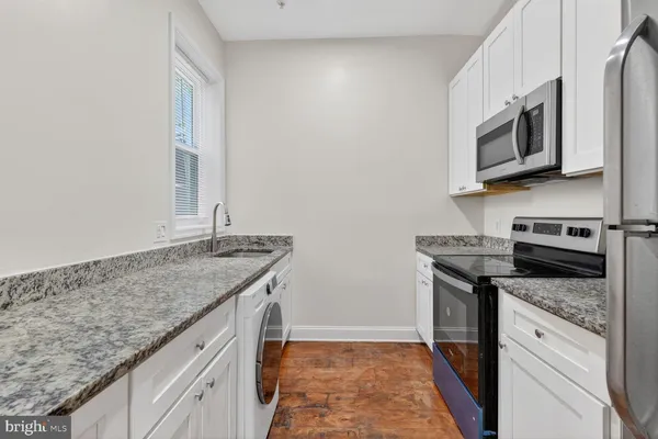 a utility room with granite countertop cabinets washer and dryer