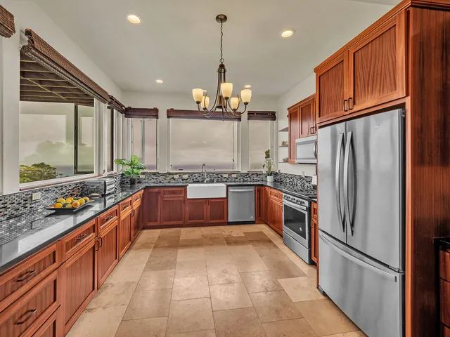 a large kitchen with stainless steel appliances kitchen island granite countertop a refrigerator and a sink