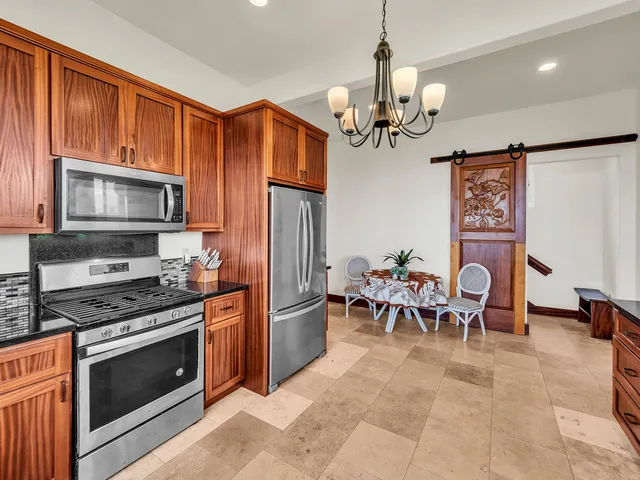 a kitchen with stainless steel appliances granite countertop a stove top oven a sink dishwasher a dining table and chairs with wooden floor