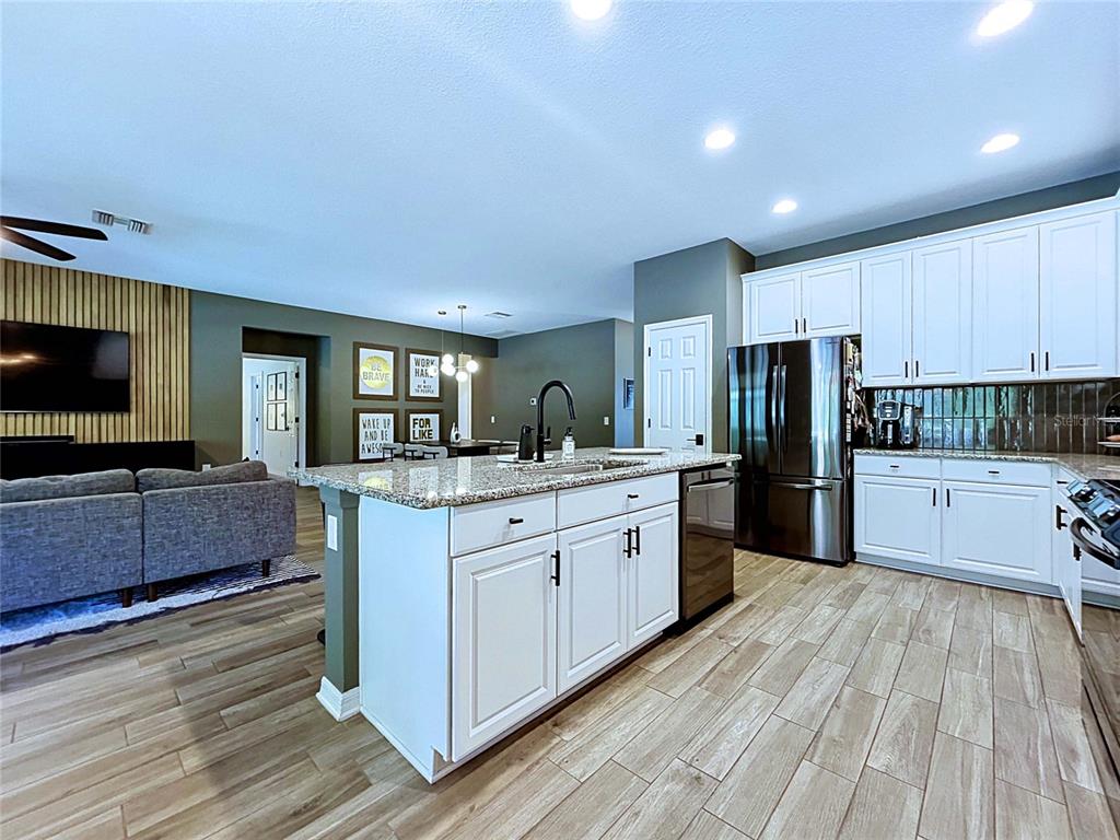 18078 Romanesque Court Spring Hill, FL 34610 - Photo 13 of 81 a kitchen with stainless steel appliances kitchen island granite countertop a stove top oven a sink dishwasher a refrigerator and cabinets with wooden floor