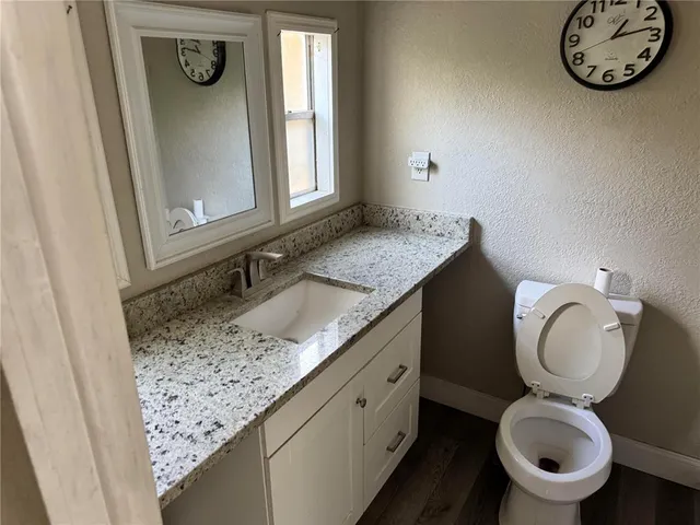 a bathroom with a granite countertop toilet sink and mirror