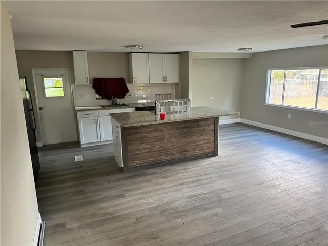 a living room with stainless steel appliances kitchen island granite countertop a stove a sink and a refrigerator