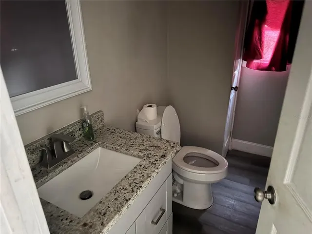 a bathroom with a sink toilet and wooden floor