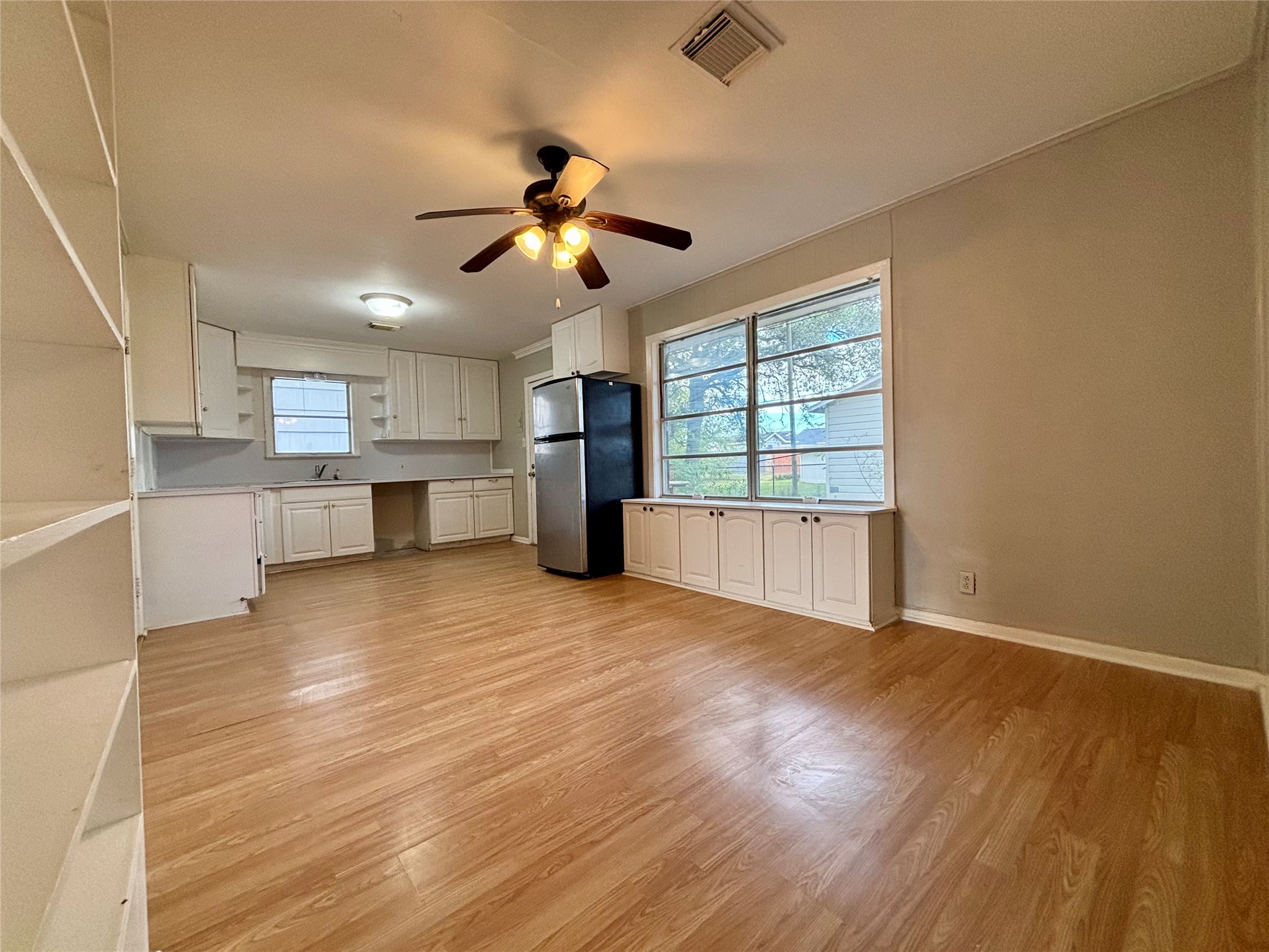 706 West 7th Street Freeport, TX 77541 - Photo 13 of 22 a view of a kitchen with a stove cabinets wooden floor and a ceiling fan