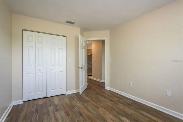 a view of an empty room with closet and wooden floor
