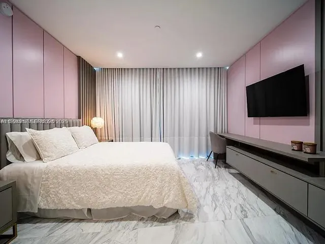 a spacious bedroom with a bed and a flat screen tv