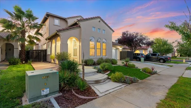 a front view of a house with a garden and trees