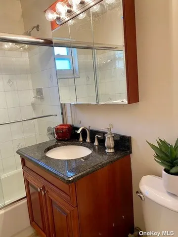a bathroom with a granite countertop sink a toilet and mirror