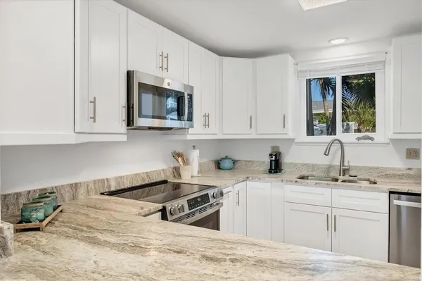 a kitchen with stainless steel appliances granite countertop a sink a stove and a microwave