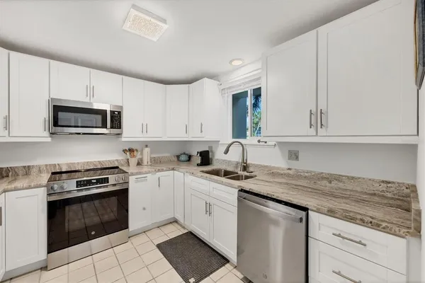 a kitchen with granite countertop white cabinets white stainless steel appliances and a sink