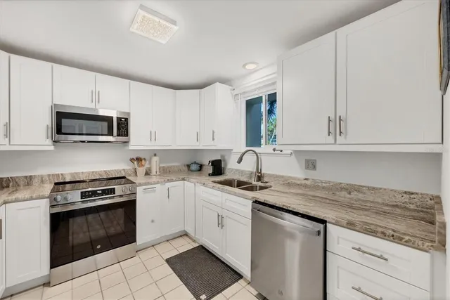 a kitchen with stainless steel appliances granite countertop white cabinets sink and window