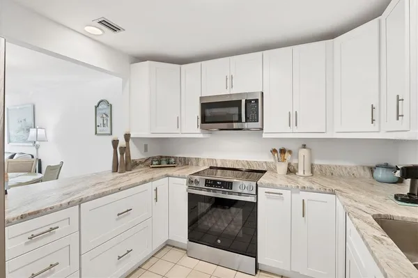 a kitchen with granite countertop white cabinets white stainless steel appliances and a sink