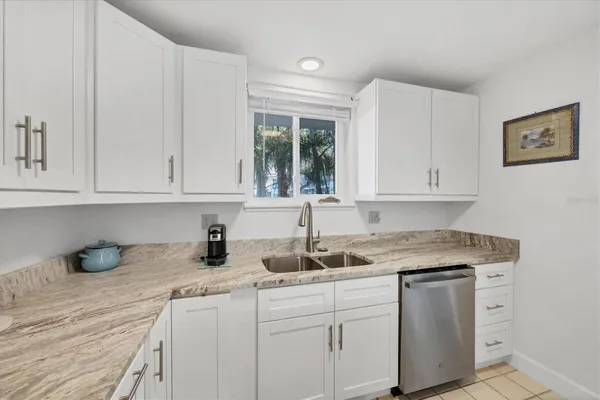 a kitchen with stainless steel appliances granite countertop white cabinets sink and window