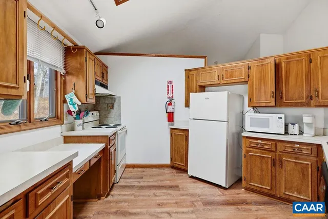 a kitchen with a refrigerator a stove top oven a sink and dishwasher with wooden floor