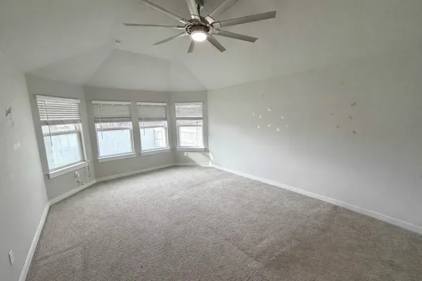 an empty room with chandelier fan and windows
