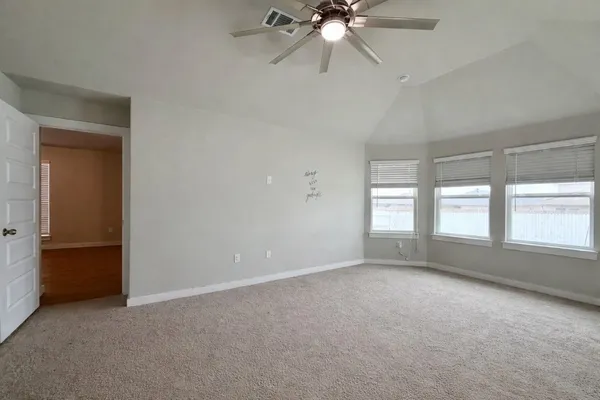 an empty room with chandelier fan and windows