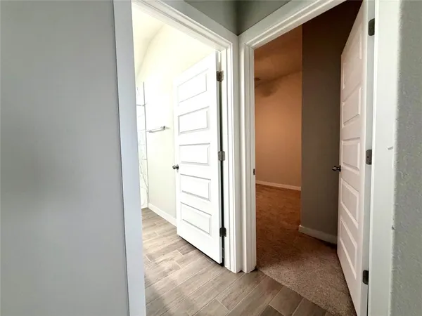 a view of a hallway with wooden floor and a room