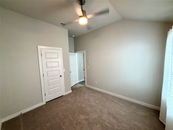 an empty room with closet and a ceiling fan