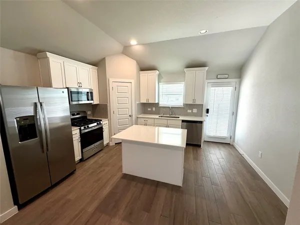 a kitchen with stainless steel appliances a refrigerator a stove a sink and white cabinets