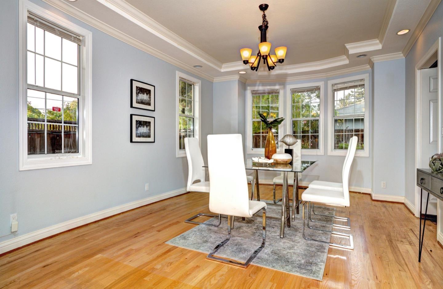 10171 Carmen Road Cupertino, CA 95014 - Photo 12 of 42 a dining room with wooden floor a chandelier a wooden table and chairs