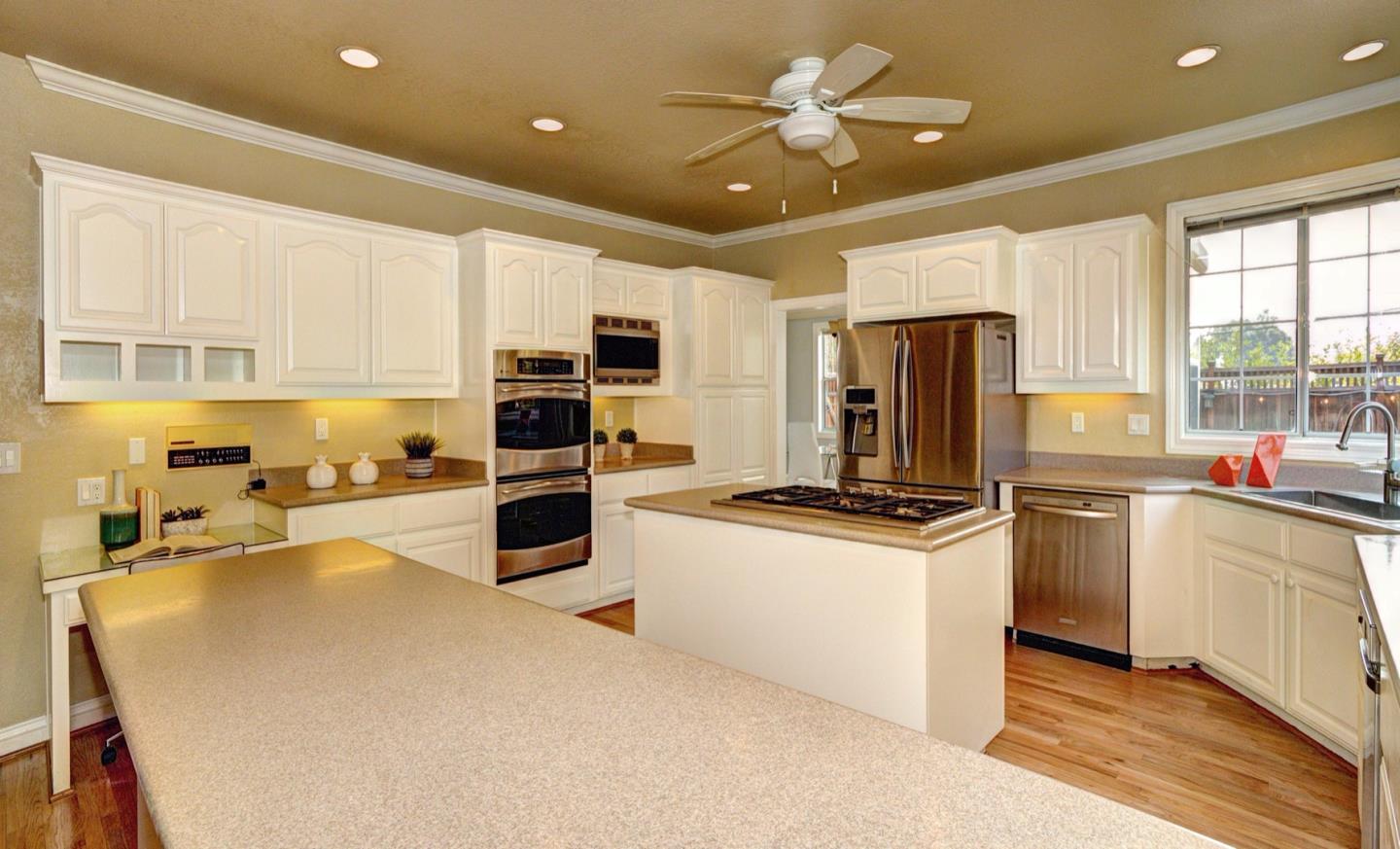 10171 Carmen Road Cupertino, CA 95014 - Photo 15 of 42 a kitchen with stainless steel appliances a stove a sink a microwave a refrigerator a center island and cabinets