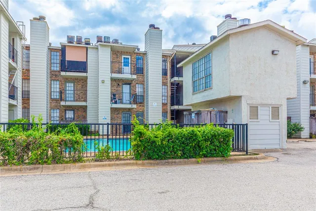 a front view of a residential apartment building with a garden and entryway