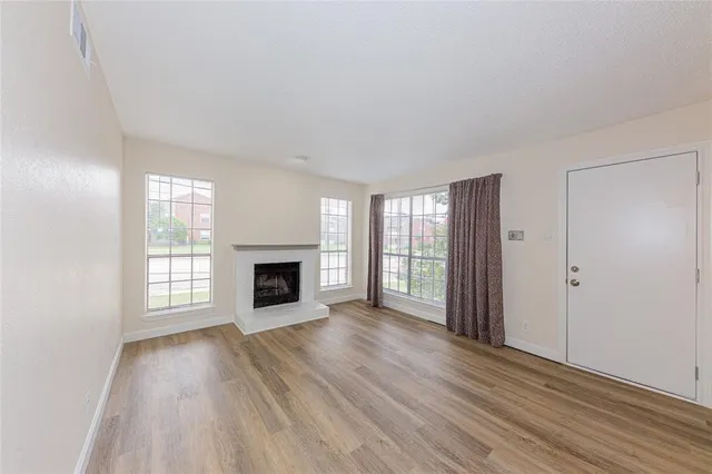 wooden floor fireplace and windows in an empty room