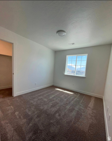 7303 North Hidden Loop Road Eagle Mountain, UT 84005 - Photo 11 of 11 Neutral wall tones, recessed window, dark plush carpeting, and a flush-mount ceiling light