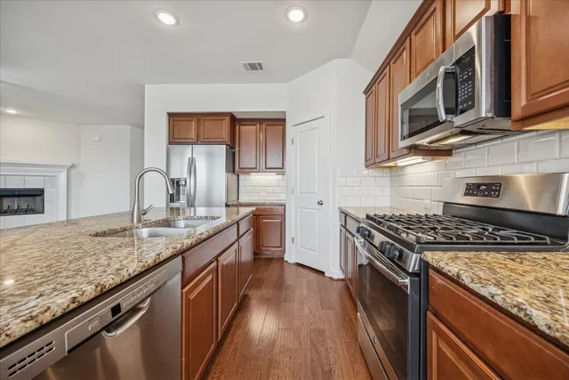 a kitchen with granite countertop stainless steel appliances and wooden cabinets