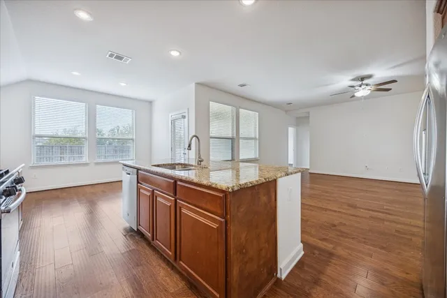 a kitchen with stainless steel appliances granite countertop a stove and a wooden floors