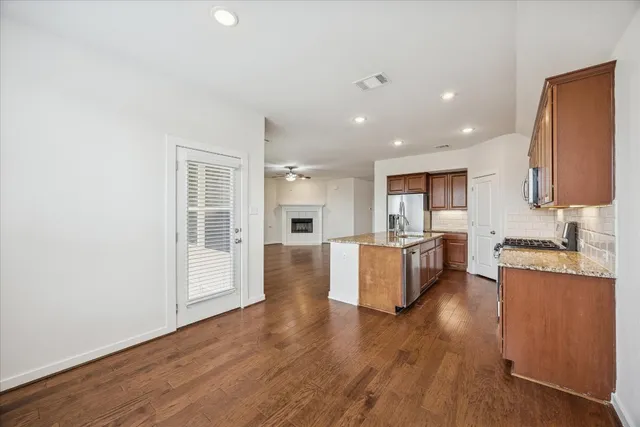 a large kitchen with a center island wooden floor and stainless steel appliances