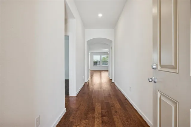 a view of a hallway with wooden floor and a bathroom