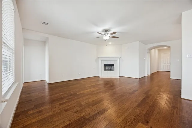 an empty room with wooden floor and ceiling fan