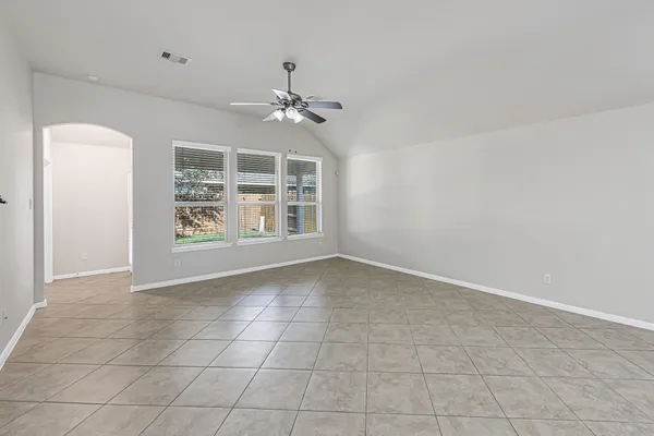 an empty room with windows and ceiling fan