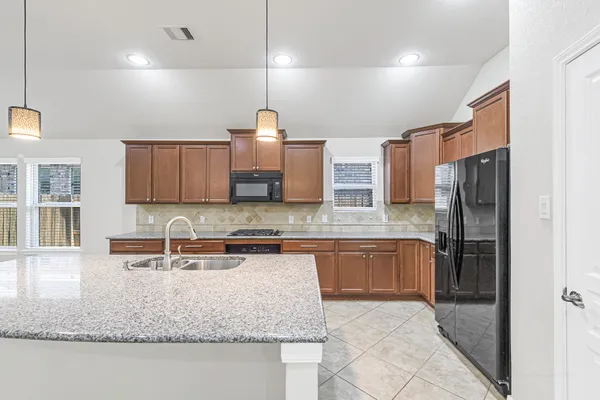 a kitchen with kitchen island granite countertop a sink a counter top space appliances and cabinets
