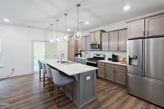 a kitchen with kitchen island wooden floors white appliances and chairs